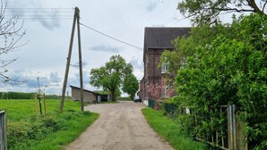 Un camino rural que conduce a un edificio de ladrillo con techo inclinado.