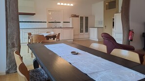 Una cocina moderna con armarios blancos, una mesa de comedor con camino de mesa blanco y un extintor de incendios en la pared.