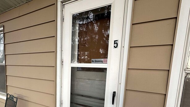A white front door with a 'No Smoking' sign, a mailbox, and a number '5' on the wall.