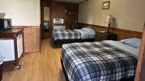 Une chambre d’hôtel compacte comprenant deux lits, un bureau avec un ordinateur et une petite kitchenette.