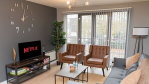 A living room with a TV, leather chairs, a sofa, and a coffee table.