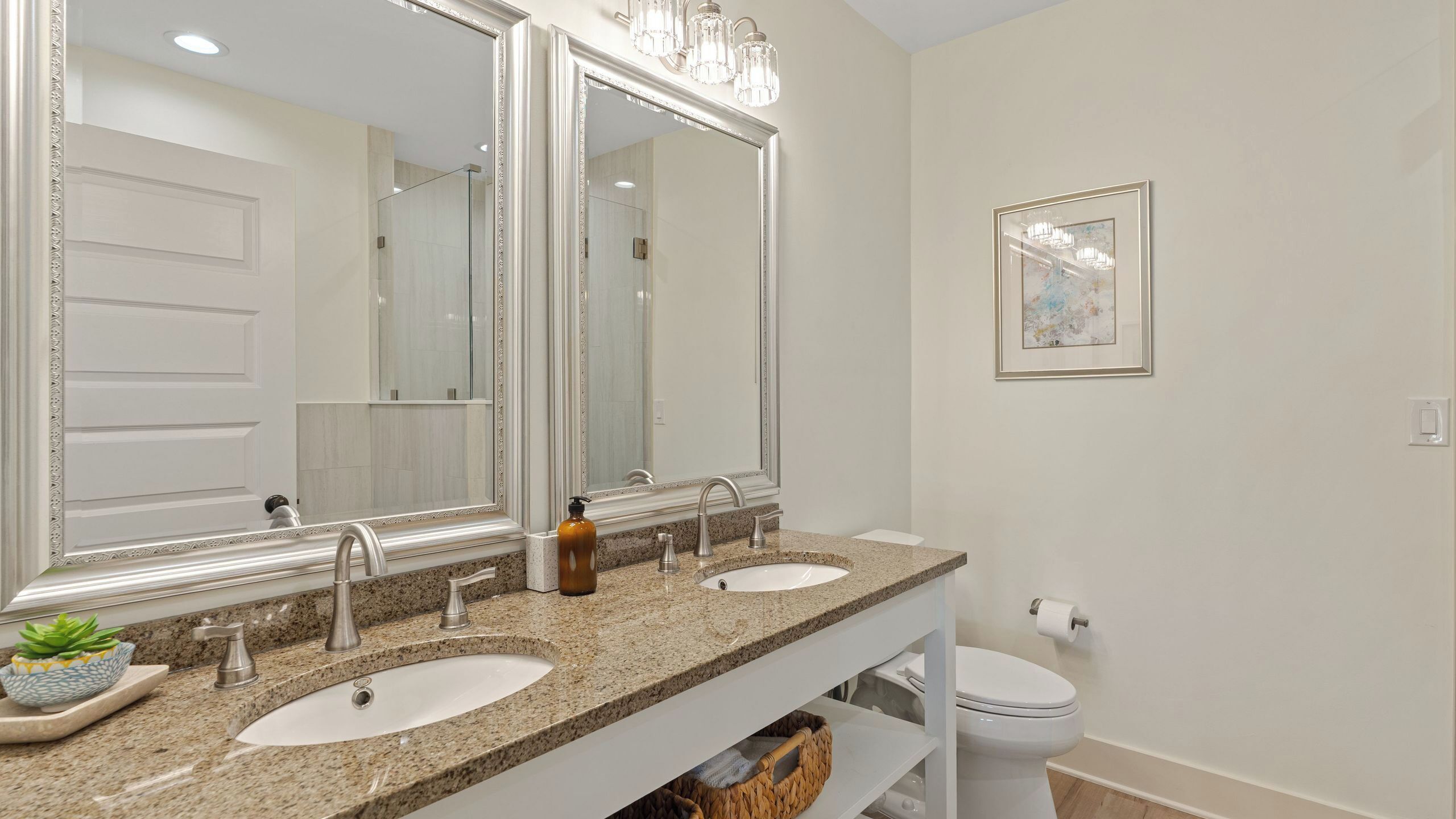 A bathroom with two sinks, a large mirror, and a toilet.