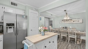 A kitchen with a stainless steel refrigerator, a water dispenser, and a wooden island with a vase of flowers. - Walk to Blue Mountain Beach, Private Pool, Hot Tub 30A Sea-renity by Avantstay (Santa Rosa Beach)