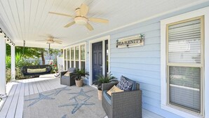 A covered porch with wicker furniture, a star-patterned rug, and a sign reading "SEA-RENIT". - Walk to Blue Mountain Beach, Private Pool, Hot Tub 30A Sea-renity by Avantstay (Santa Rosa Beach)