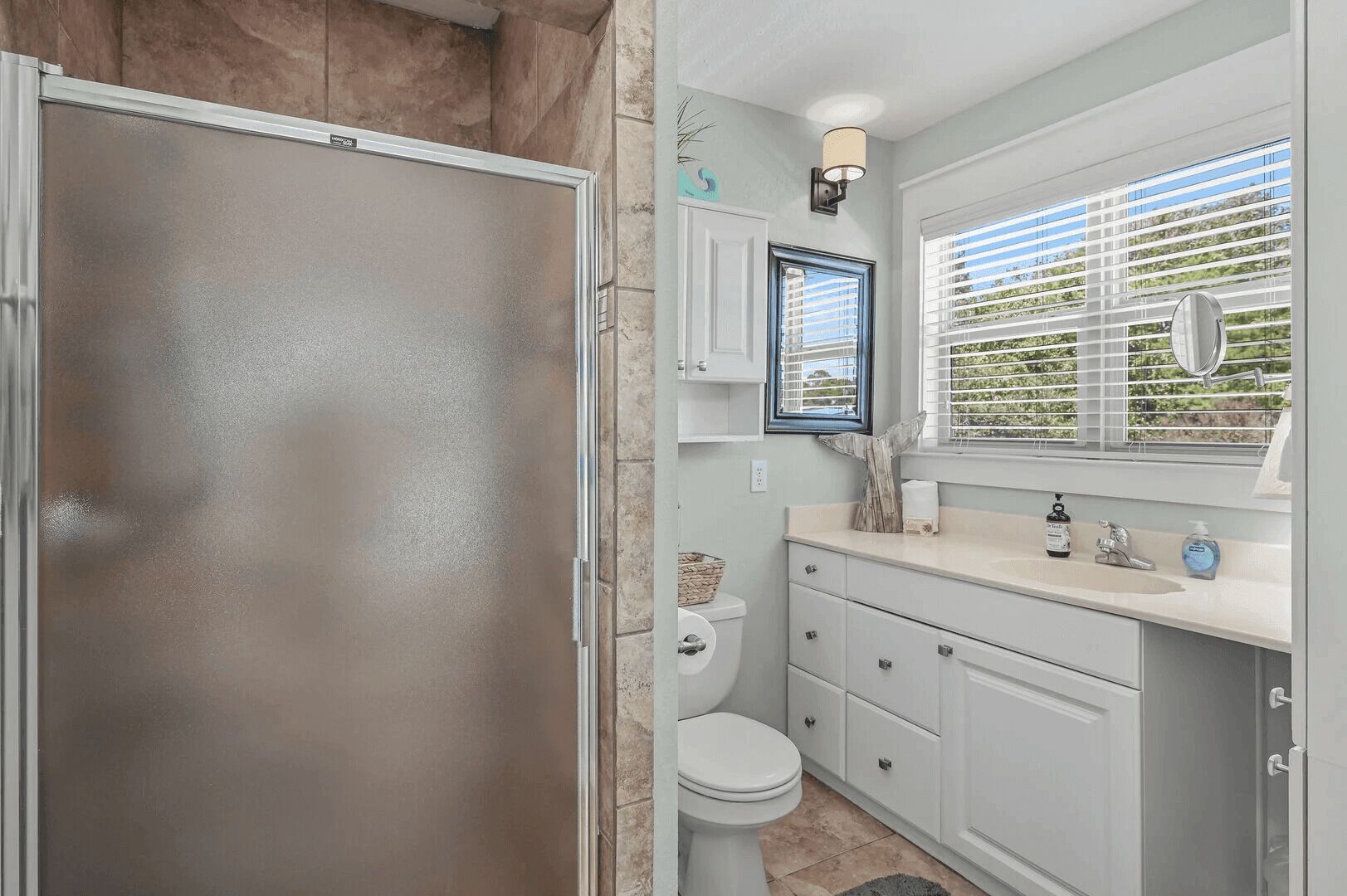 A bathroom with a shower, toilet, and vanity with a sink and mirror.