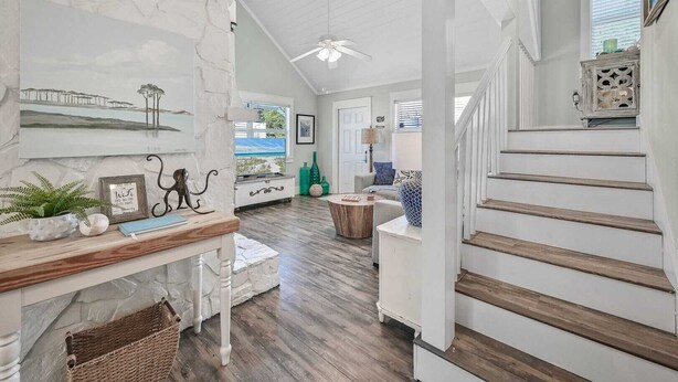 A spacious living area with a wooden staircase, a fireplace, and a view of the outdoors. - Walk to Blue Mountain Beach, Private Pool, Hot Tub 30A Sea-renity by Avantstay (Santa Rosa Beach)