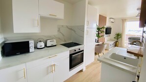 A modern kitchen with white cabinetry, a built-in oven, a microwave, and a toaster. - Studio Cocoon, sea and marina view. (Marigot)