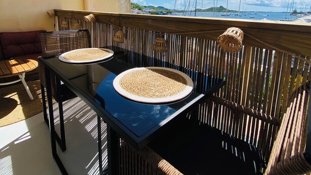 A balcony with a table and chairs, overlooking a marina with boats. - Studio Cocoon, sea and marina view. (Marigot)