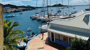 A marina with boats docked, a building with a sign for diesel marine services, and a clear blue sky with clouds. - Studio Cocoon, sea and marina view. (Marigot)