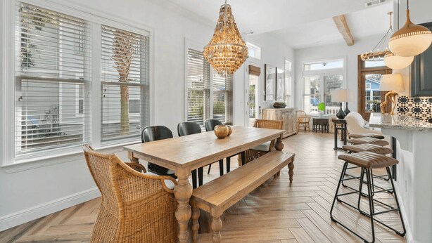 A spacious dining area with a wooden table, wicker chairs, and a large chandelier.