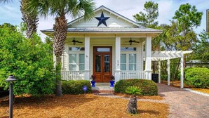 A house with a star on the roof, a porch, and a well-maintained garden.