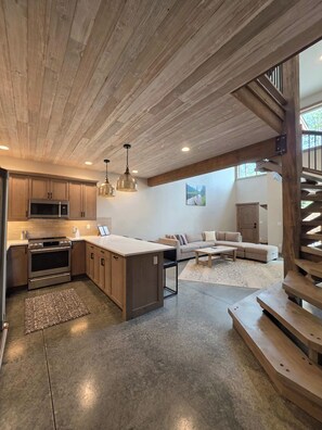 A modern kitchen with a central island, stainless steel appliances, and wooden ceiling beams. - Glacier Luxury Stay • Priv Hot Tub Condo•  2BR/2BA (Coram)