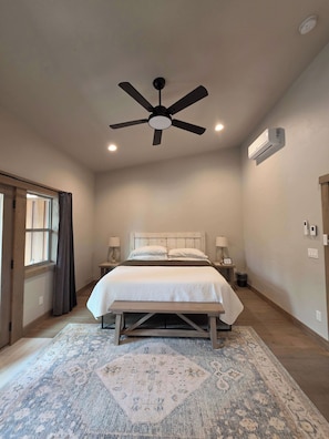 A bedroom with a bed, bedside lamps, a ceiling fan, an air conditioning unit, and a patterned rug. - Glacier Luxury Stay • Priv Hot Tub Condo•  2BR/2BA (Coram)