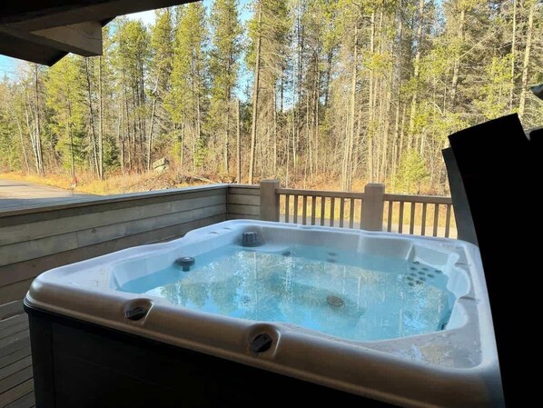 A hot tub on a wooden deck with a forest view. - Glacier Luxury Stay • Priv Hot Tub Condo• 2BR/2BA (Coram)