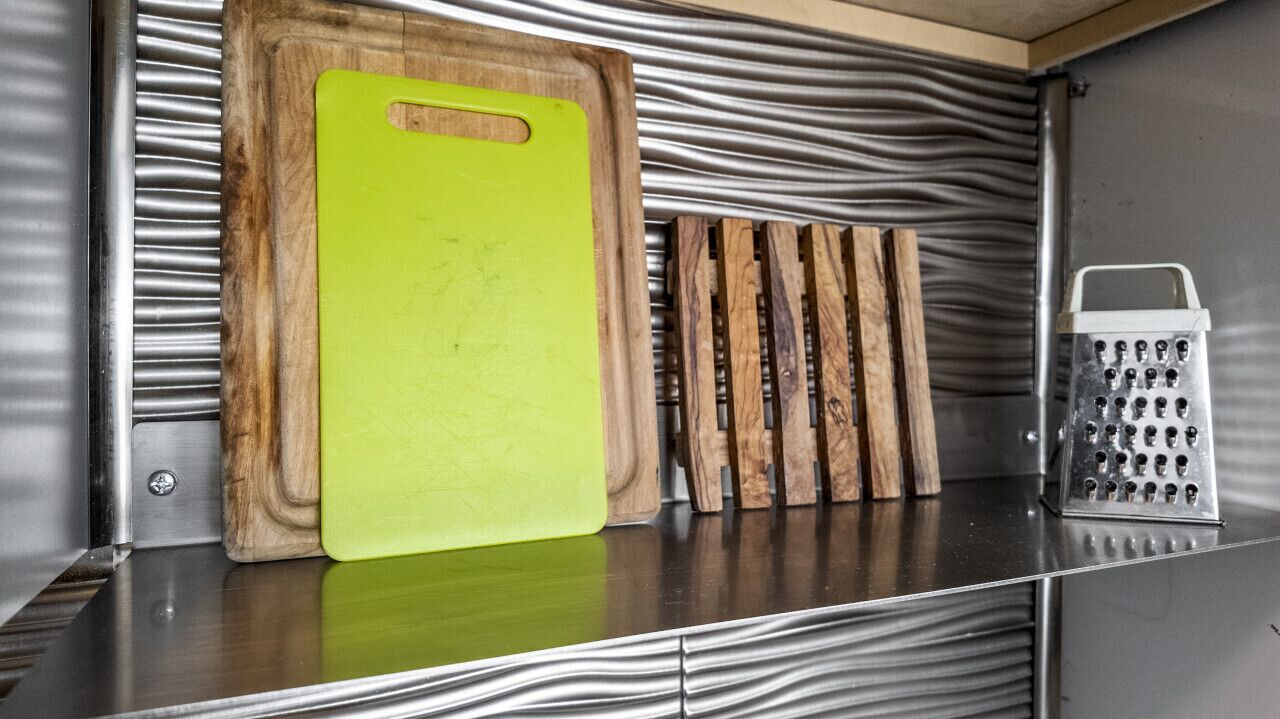 A kitchen with a wooden cutting board, a grater, and a wooden rack.