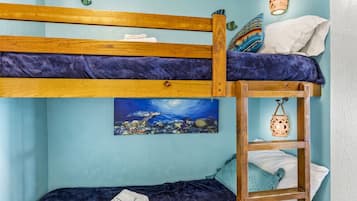 Ein Stockbett mit Holzrahmen und blauer Decke, eine Leiter und ein Bild einer Unterwasserlandschaft.