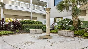 A courtyard with a central column, surrounded by planters and a palm tree.