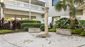 Une cour intérieure avec une colonne centrale, entourée de jardinières et d’un palmier.
