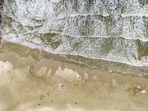Une plage où les vagues se brisent sur le rivage, une plage de sable, et quelques objets épars.