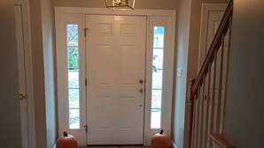 A hallway with a wooden floor, a white door, a blue rug, and a staircase with wooden railings. - Large Beautiful quality home in a quiet subdivision.  (Lynchburg)