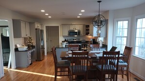 A spacious kitchen with wooden flooring, a dining area with six chairs, and a large island with a sink and microwave. - Large Beautiful quality home in a quiet subdivision.  (Lynchburg)