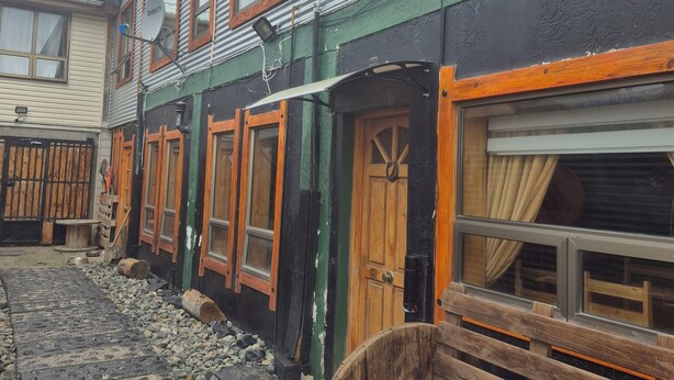 A row of traditional wooden houses with metal siding, wooden doors, and windows. - Cabaña Galvarino Puerto Natales (Natales)