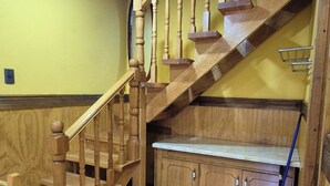 A wooden staircase with a handrail, leading to a landing with a bench and cabinets. - Cabaña Galvarino Puerto Natales (Natales)