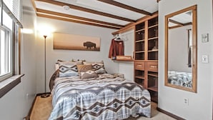 Un dormitorio con cama, armario, espejo y una obra de arte colgada en la pared.