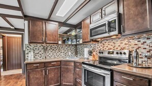 Una cocina moderna con armarios de madera oscura, estufa de acero inoxidable y salpicadero de azulejos.