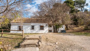 A rustic white house with a tiled roof, a wooden fence, and a stone pathway leading to the entrance. - Holiday Home 'Casa Rural La Roca' with Mountain Views, Shared Pool and Wi-Fi (La Zubia)