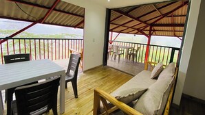 Ein Zimmer mit Holzboden, einem Bett mit Kissen, einem Tisch mit Stühlen und einem Balkon mit Geländer.