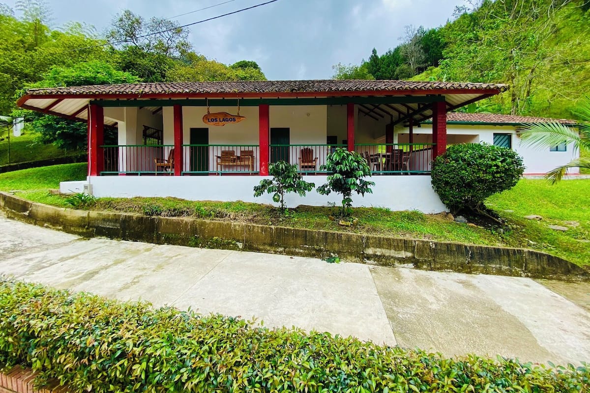 A two-story building with a red and white facade, a covered porch with chairs, and a sign reading "Los Lagos."