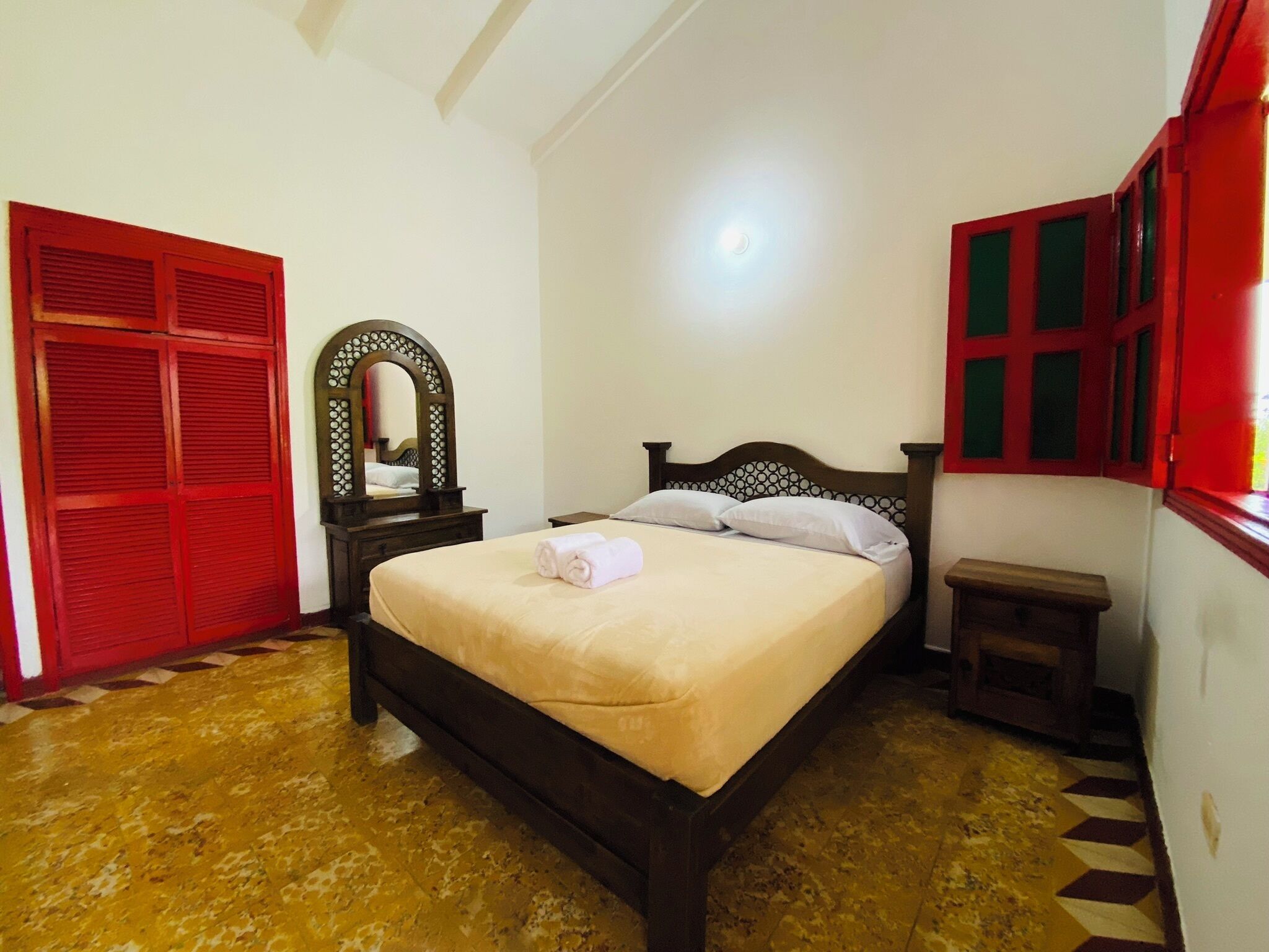 Een slaapkamer met een bed, nachtkastje, spiegel en garderobe.