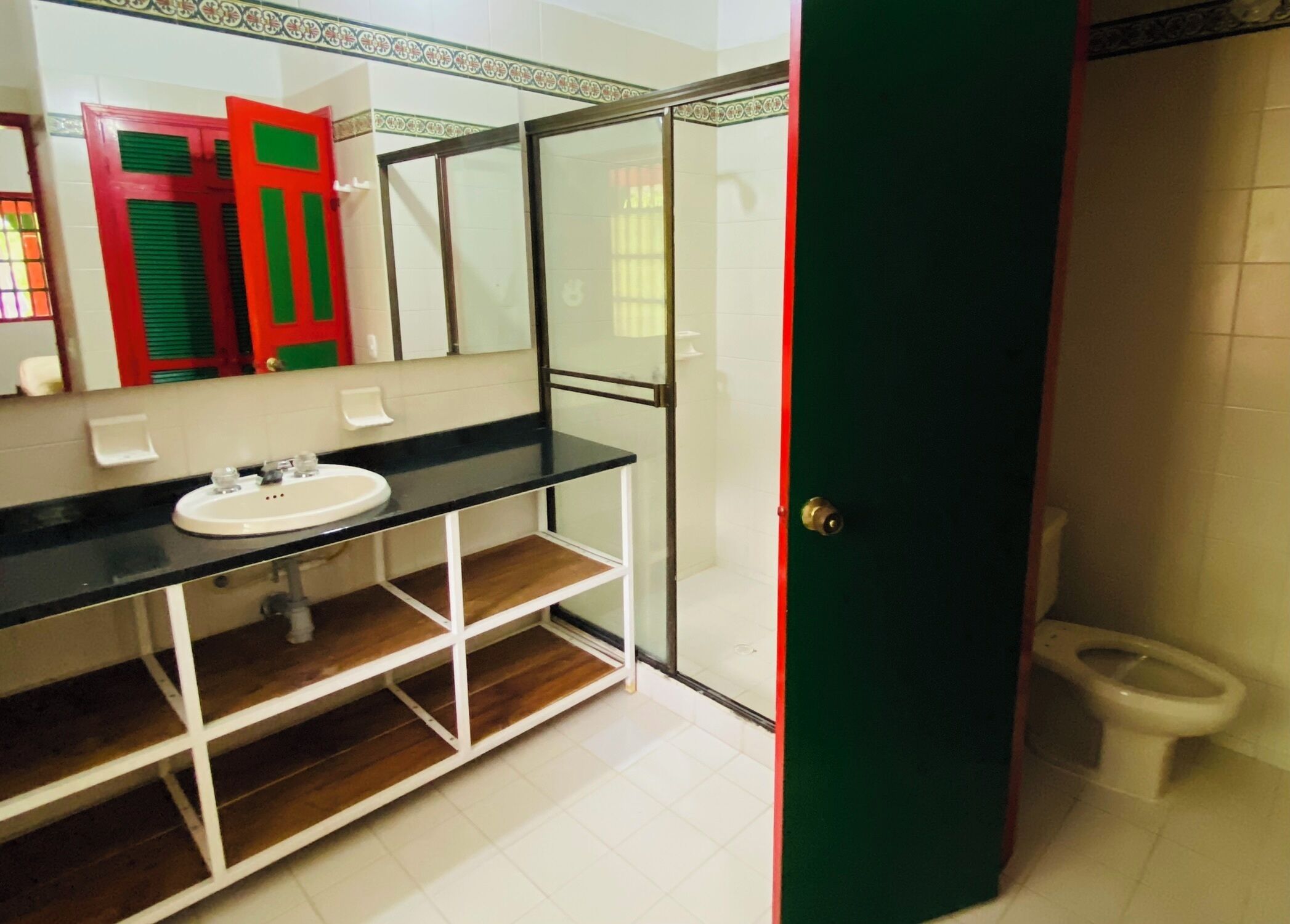 Un baño con lavamanos blanco, cabina de ducha de vidrio y un inodoro.