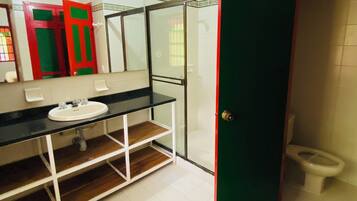 Un baño con lavamanos blanco, cabina de ducha de vidrio y un inodoro.