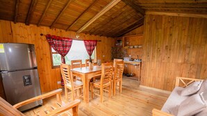 Ein Holzblockhaus-Innenraum mit Essbereich, Küche und einem Bett.