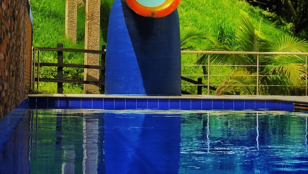 Ein Swimmingpool mit Rutsche, umgeben von üppiger Vegetation und einer Holzterrasse.