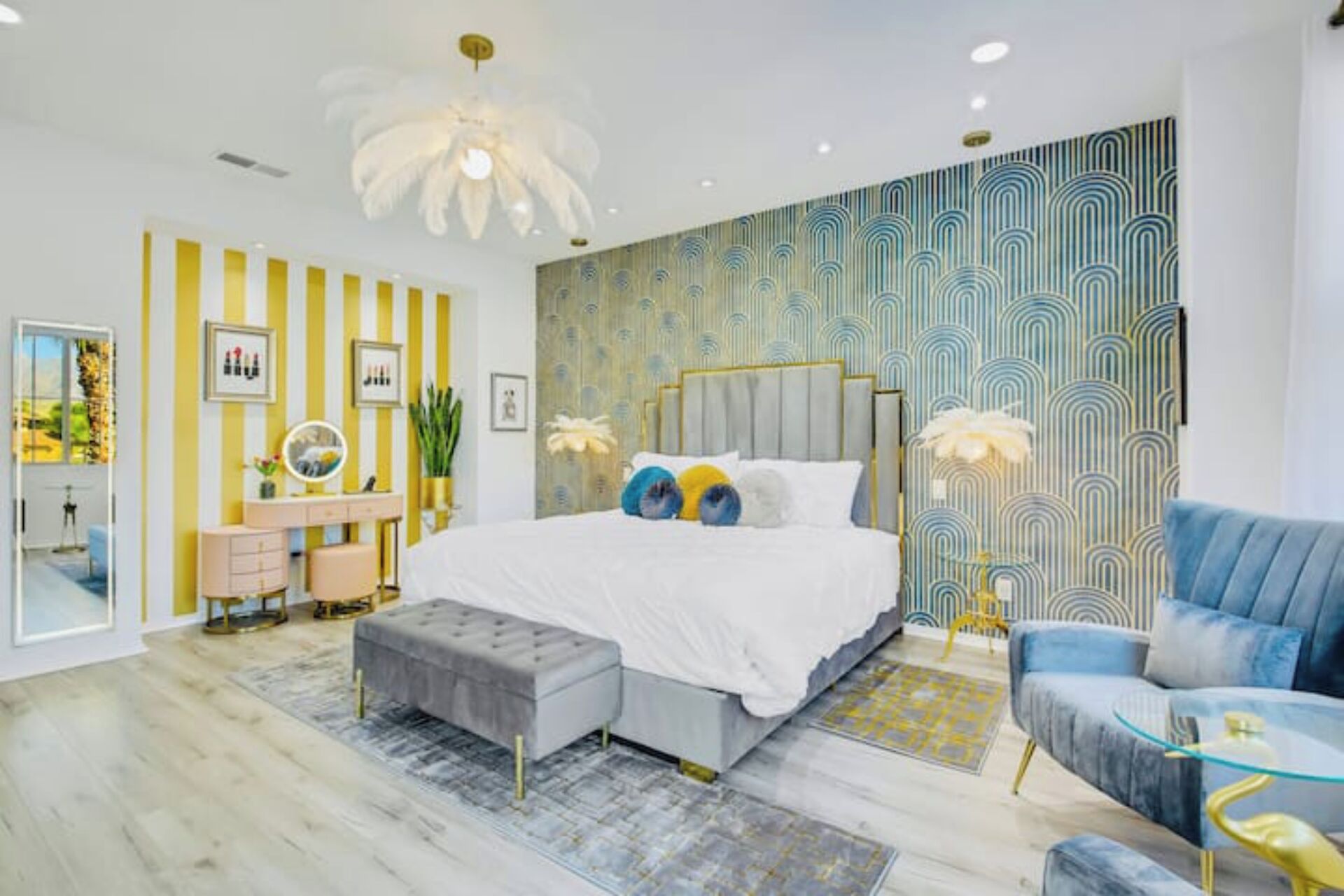 Een moderne slaapkamer met een groot bed, een kaptafel en een blauwe fauteuil.