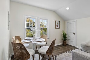 Cozy dining area with a round table for four, wicker chairs, and a potted plant.