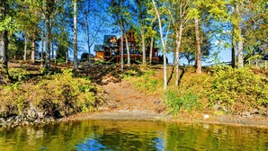 Uma cabana com um deck de madeira e vista para um lago.