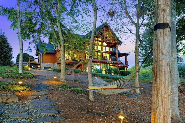 A log cabin with a stone pathway leading to it, surrounded by trees.