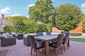 Une terrasse extérieure avec une table de billard, des meubles en osier et une table en bois.
