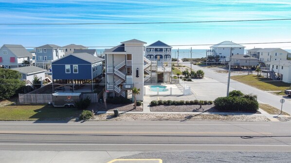 A coastal residential area with a central building featuring multiple floors, a swimming pool, and a small parking area. - Ocean and Sound Views at "Shoreline Escape"! (Surf City)