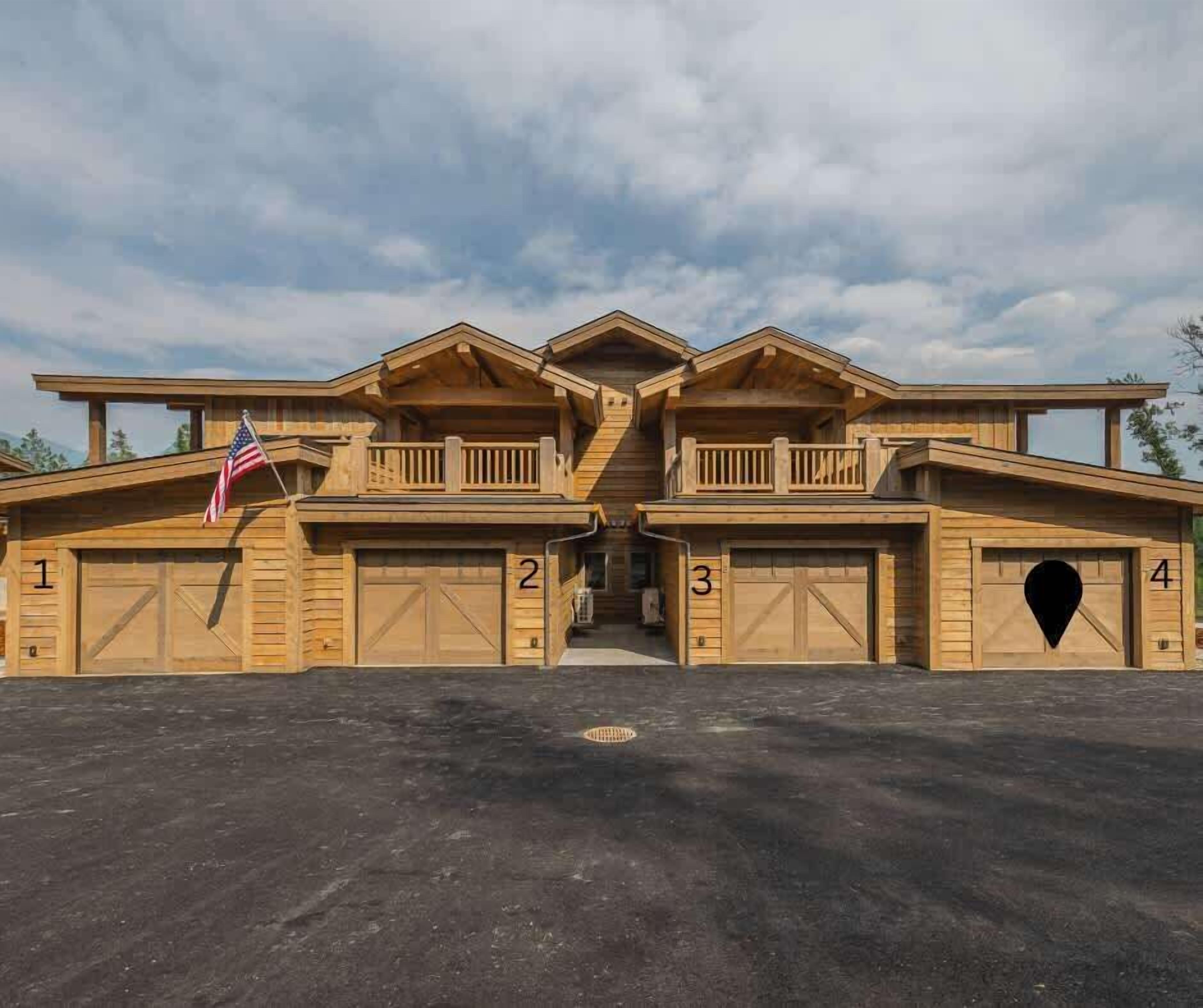 A large, two-story wooden building with four garage doors, numbered 1 to 4, and a central entrance.