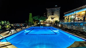 A swimming pool with a stone wall and lounge chairs. - Villa Gaia With Private Pool (Agios Nikolaos)