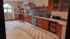 A modern kitchen with granite countertops, wooden cabinets, and a patterned floor. - Vacation apartment Wiesenblick in the Michelshof (Kevelaer)