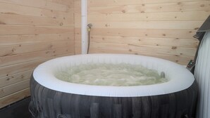 Una vasca idromassaggio in una cabina di legno con un pannello di controllo a destra.