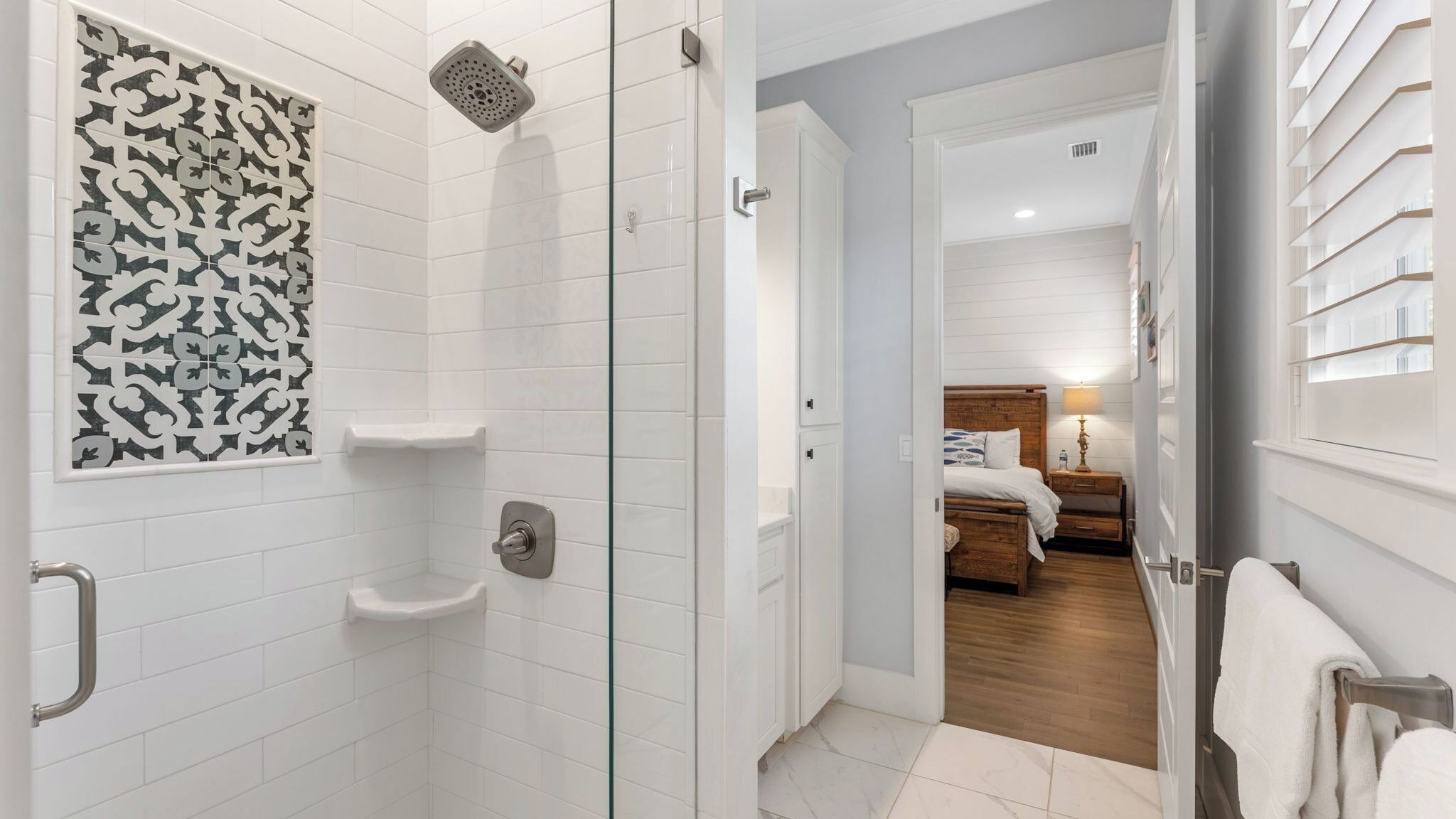 Une salle de bain moderne avec des carreaux blancs, une douche et un espace douche fermé par des parois de verre.