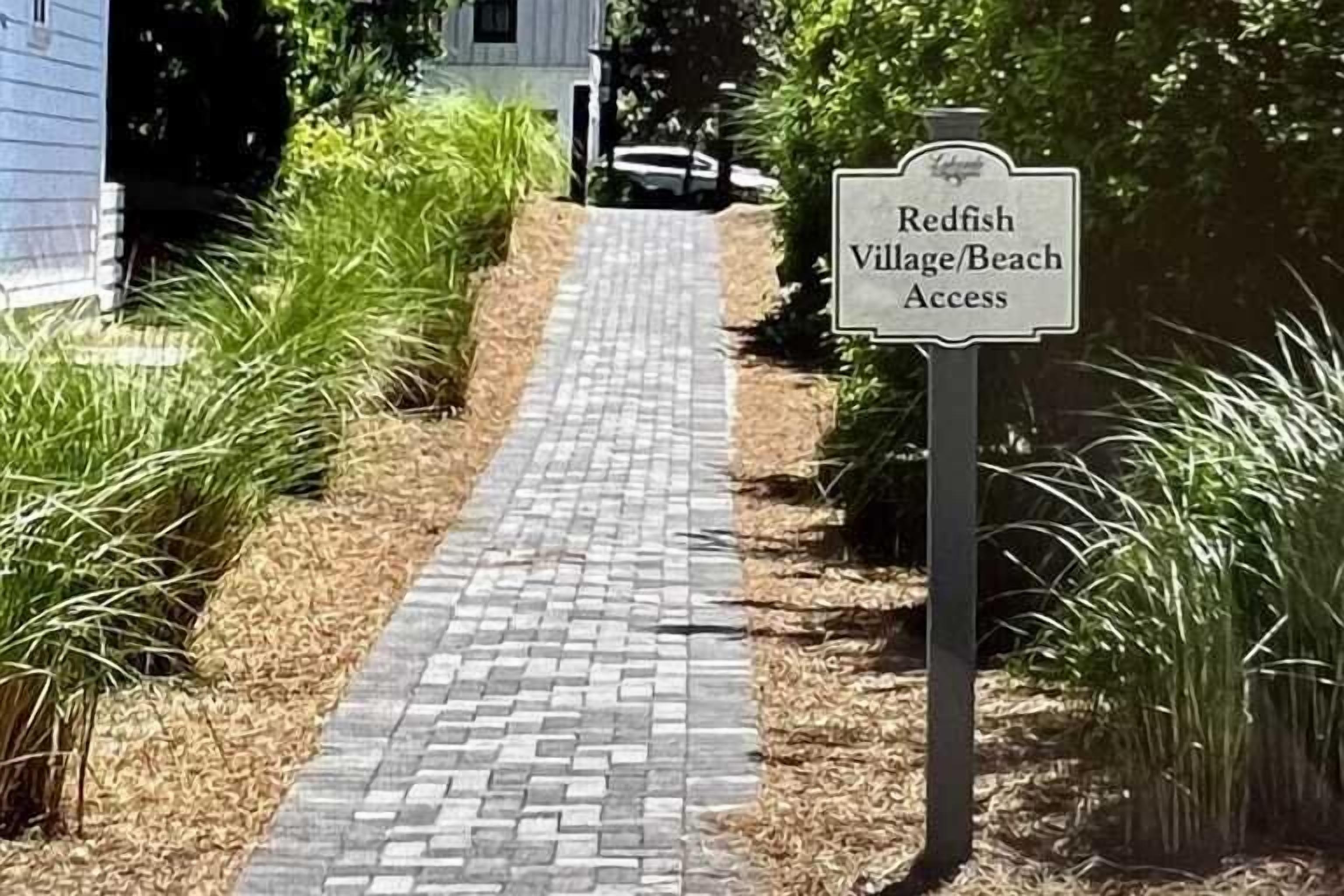 Un camino que lleva a Redfish Village/Acceso a la playa, con un cartel indicador.