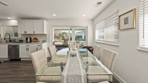 Una cocina moderna con armarios blancos, un lavavajillas de acero inoxidable y un amplio ventanal con vistas a un jardín.